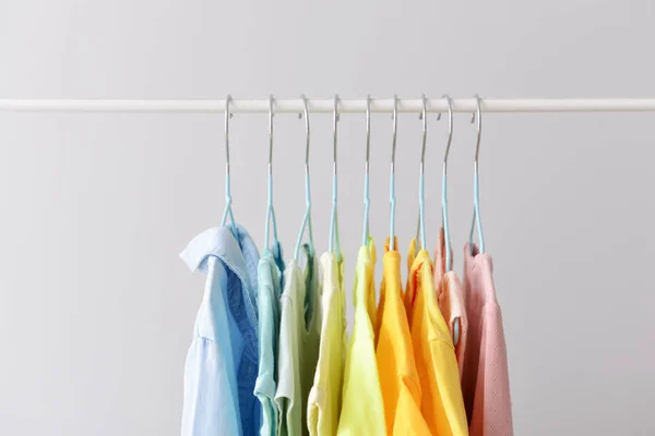 Elegante ropa de niño colgando en el estante contra el fondo claro —  Fotos de Stock