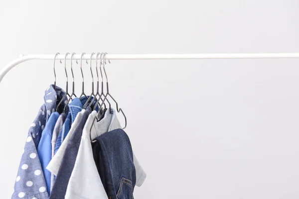 Stylish kid clothes hanging on rack against light background — Stock Photo, Image