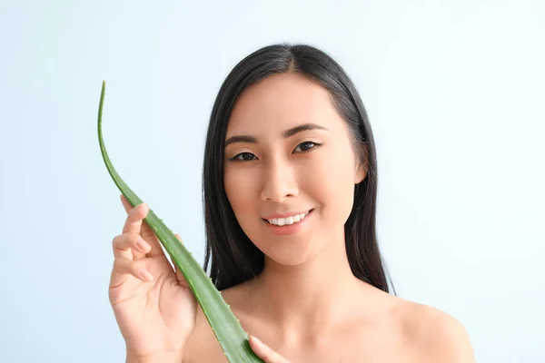 Beautiful Asian woman with aloe vera on color background — Stock Photo, Image