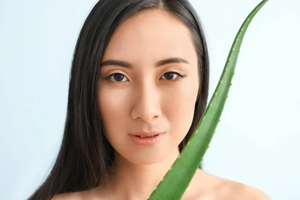 Beautiful Asian woman with aloe vera on color background — Stock Photo, Image