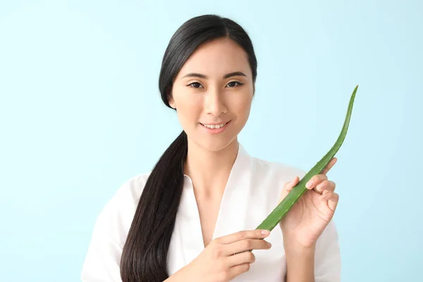 Beautiful Asian woman with aloe vera on color background — Stock Photo, Image