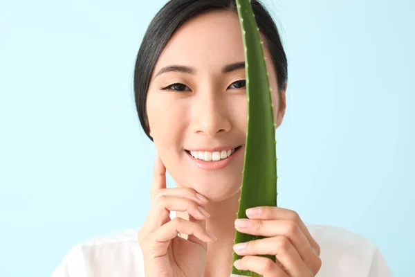 Beautiful Asian woman with aloe vera on color background — Stock Photo, Image