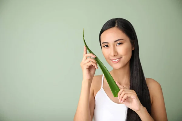 Beautiful Asian woman with aloe vera on color background — Stock Photo, Image