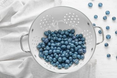 Beyaz masada taze yaban mersini ile Colander