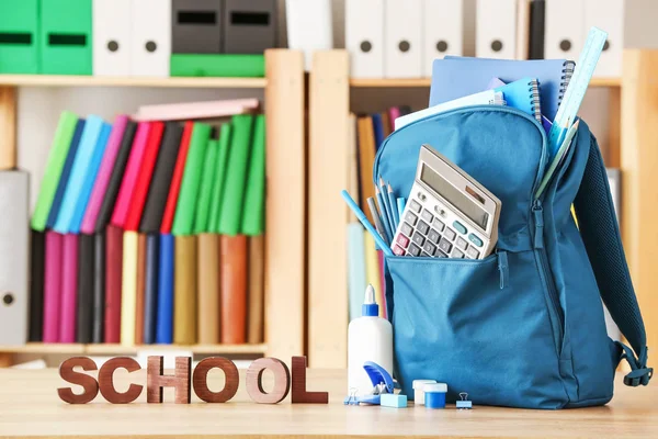 Sac à dos scolaire avec papeterie sur la table en classe — Photo