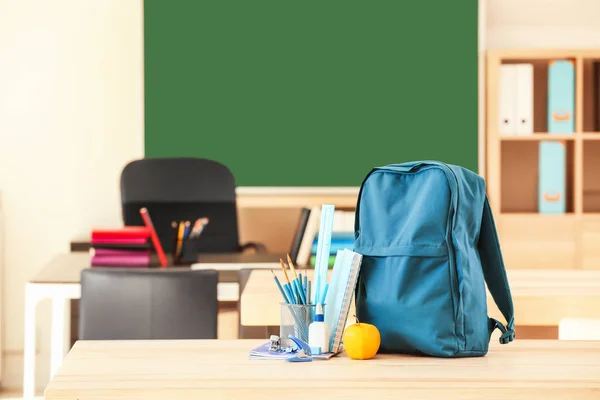 Mochila escolar con papelería en la mesa en el aula —  Fotos de Stock