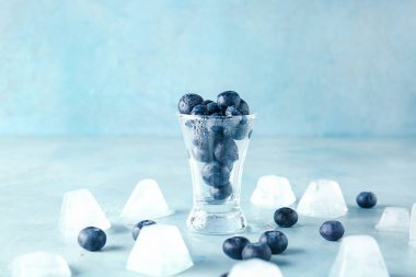 Renk arka planda taze yaban mersini ve buz küpleri ile Cam