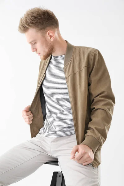 Stylish young man sitting on stool against white background — Stock Photo, Image