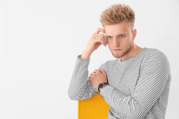 Stylish young man sitting on chair against white background — Stock Photo, Image