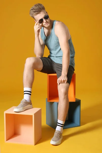 Stylový mladý muž ve sportovním oblečení na barevném pozadí — Stock fotografie