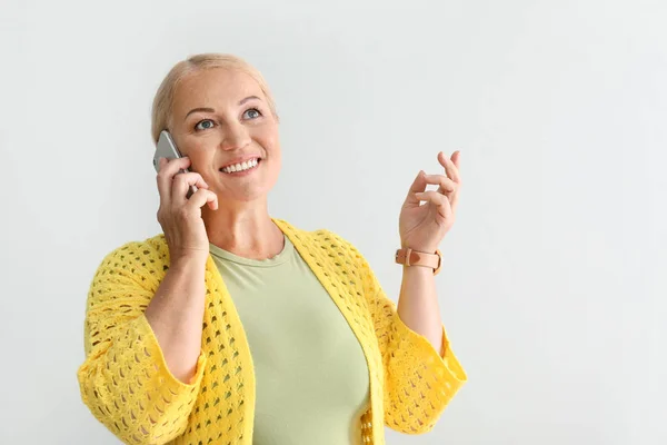 Stijlvolle rijpe vrouw praten door mobiele telefoon op lichte achtergrond — Stockfoto