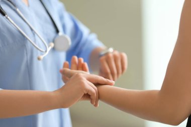 Klinikte genç kadının nabzını ölçen doktor