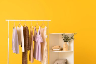 Renkli duvara yakın asılı giysiler ile Raf