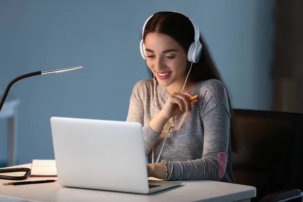 Female student with laptop listening to music while preparing for exam at home — Stock Photo, Image