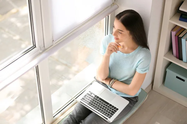 Vrouwelijke student met laptop voorbereiding voor examen in de buurt van venster — Stockfoto
