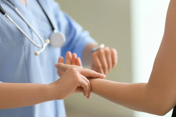 Doctor measuring pulse of young woman in clinic — Stock Photo, Image