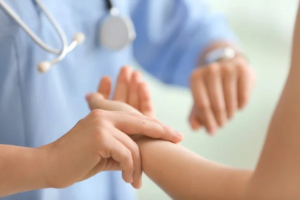 Doctor measuring pulse of young woman in clinic — Stock Photo, Image