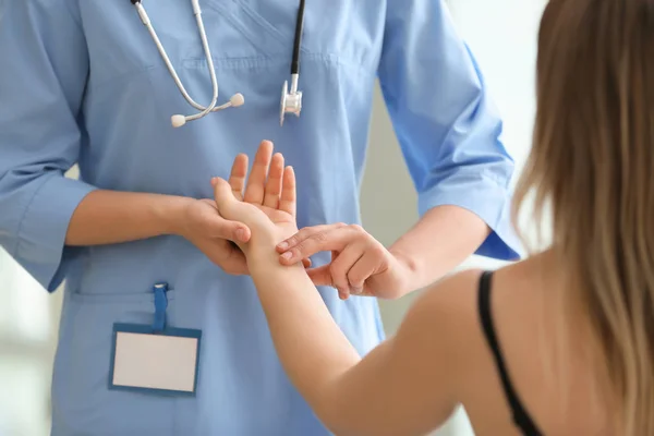 Doktor měří pulz mladé ženy na klinice. — Stock fotografie