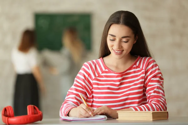 Jonge vrouwelijke student voorbereiding voor examen in klaslokaal — Stockfoto