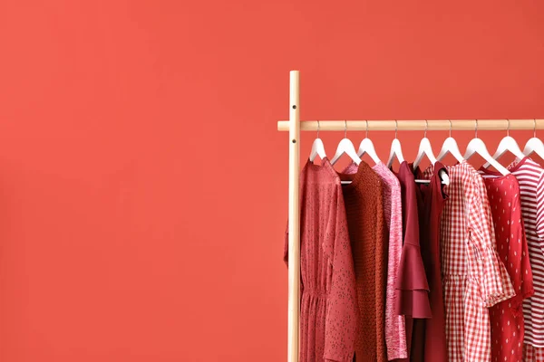 Cremalheira com roupas penduradas no fundo de cor — Fotografia de Stock