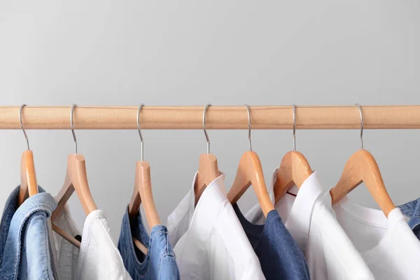 Rack with hanging clothes on light background — Stock Photo, Image