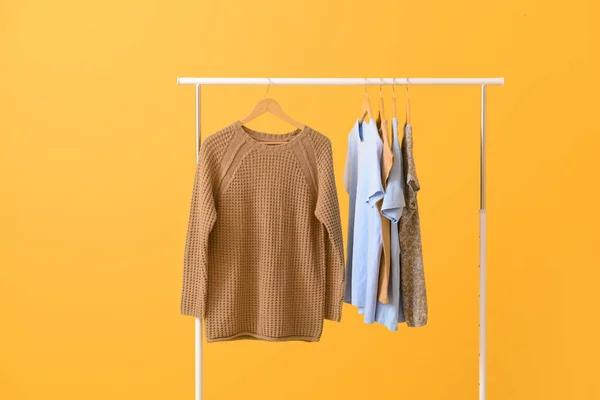 Rack med hängande kläder på färg bakgrund — Stockfoto