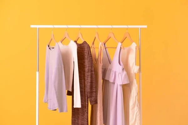 Rack with hanging clothes on color background — Stock Photo, Image