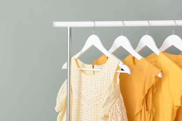 Rack with hanging clothes on color background — Stock Photo, Image