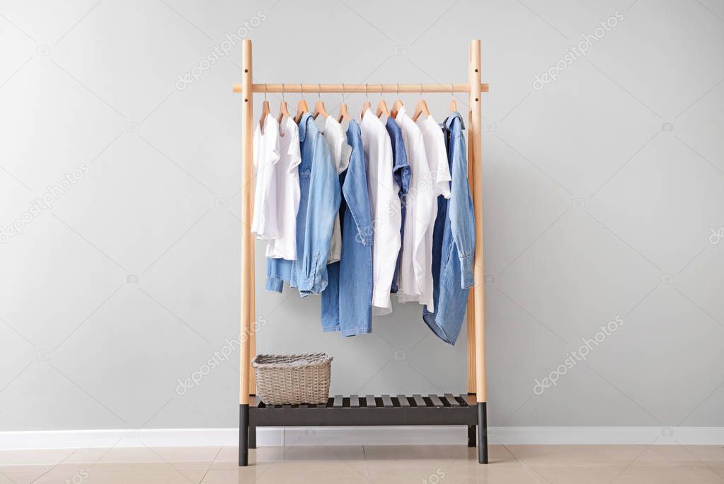 Rack with hanging clothes near light wall