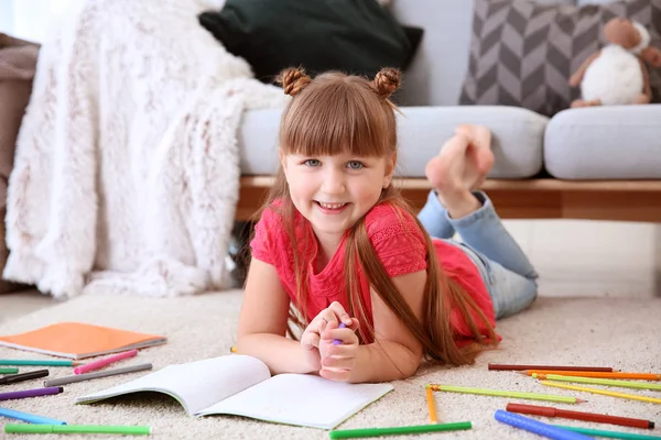 Bonito desenho menina enquanto deitado no tapete — Fotografia de Stock