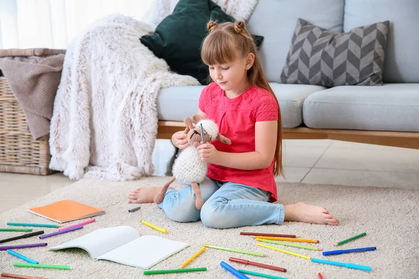 Cute little girl drawing while sitting on carpet — Stock Photo, Image