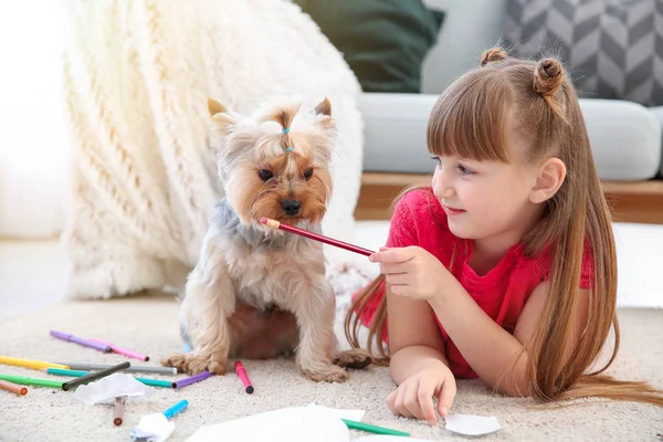 Little girl with cute dog drawing while lying on carpet — Stock Photo, Image