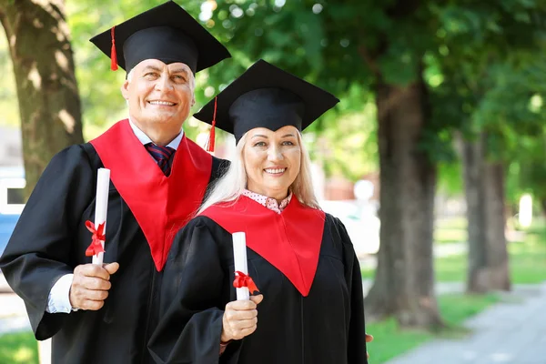 Mature couple in bachelor robes outdoors — Stock Photo, Image