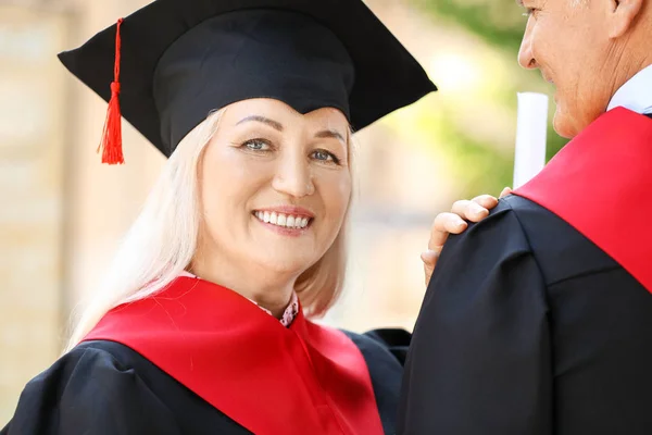 Mature couple in bachelor robes outdoors — Stock Photo, Image