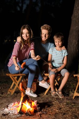 Aile akşam kamp ateşi üzerinde sosis kavurma