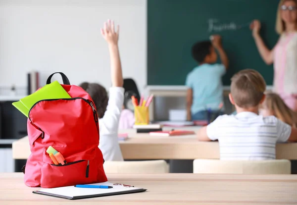 Iskolai hátizsák írószerrel az asztalon az osztályteremben — Stock Fotó