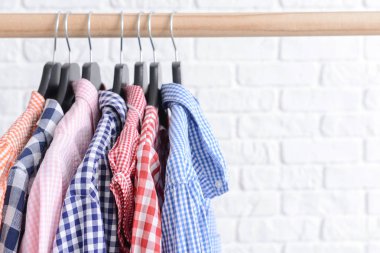 Beyaz tuğla duvara karşı asılı giysiler ile Raf