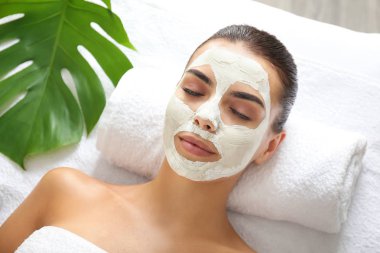 Spa salonunda rahatlatıcı yüz maskesi ile güzel genç kadın