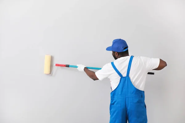 African-American decorator painting light wall — Stock Photo, Image