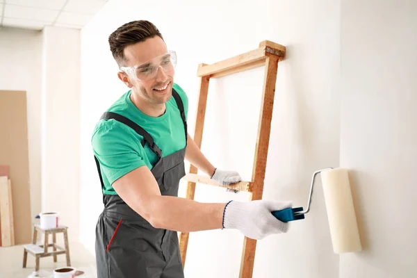 Male decorator painting light wall — Stock Photo, Image