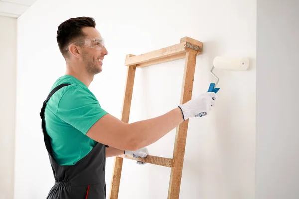 Male decorator painting light wall — Stock Photo, Image