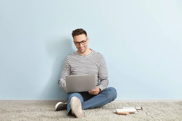 Male blogger with laptop sitting near color wall — Stock Photo, Image