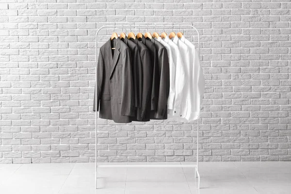 Rack with hanging clothes against brick wall — Stock Photo, Image