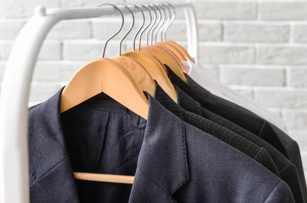 Rack with hanging clothes against brick wall, closeup — Stock Photo, Image