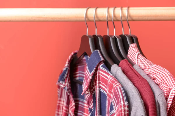 Rack with hanging clothes on color background — Stock Photo, Image