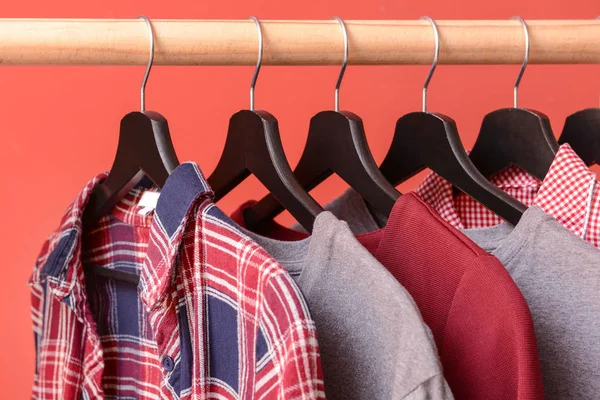 Rek met hangende kleren op kleur achtergrond — Stockfoto