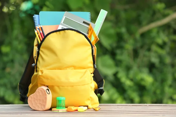 Mochila escolar con papelería en la mesa al aire libre —  Fotos de Stock