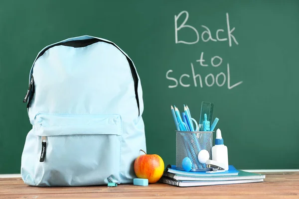 Mochila escolar con papelería en la mesa en el aula —  Fotos de Stock