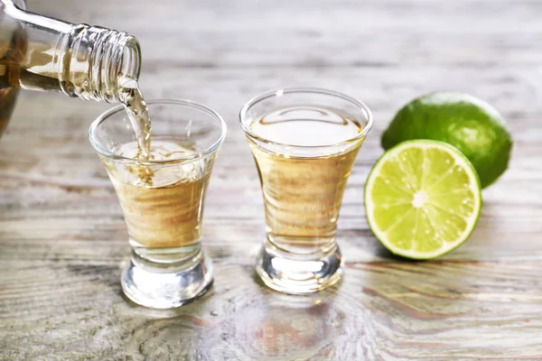 Pouring of tequila in glass on table — Stock Photo, Image