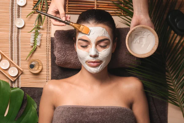 Косметолог надевает маску на лицо женщины в спа-салоне — стоковое фото